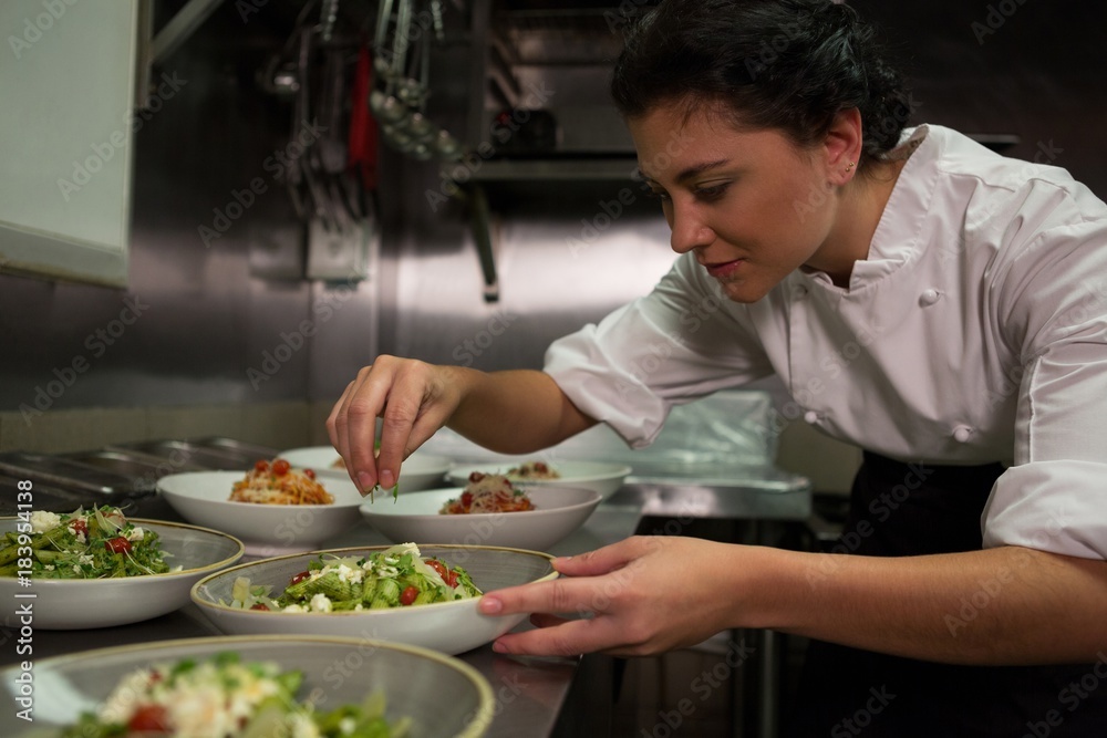 Female chef garnishing appetizer plates at order station Female chef garnishing appetizer plates at order station