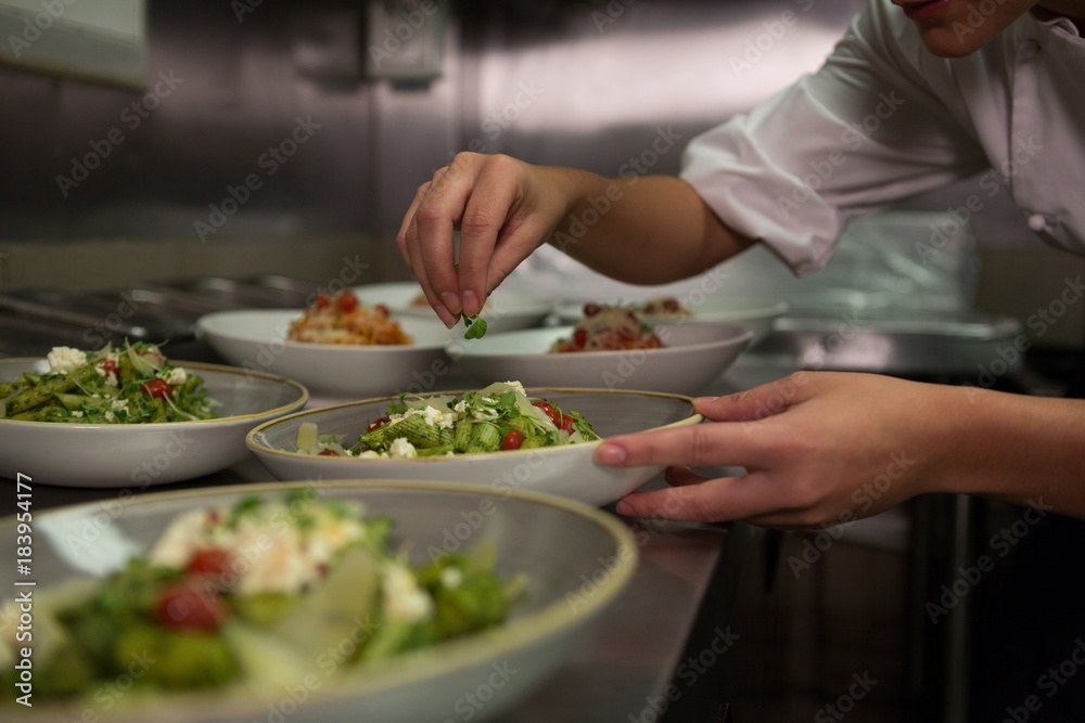 Female chef garnishing appetizer plates at order station Female chef garnishing appetizer plates at order station