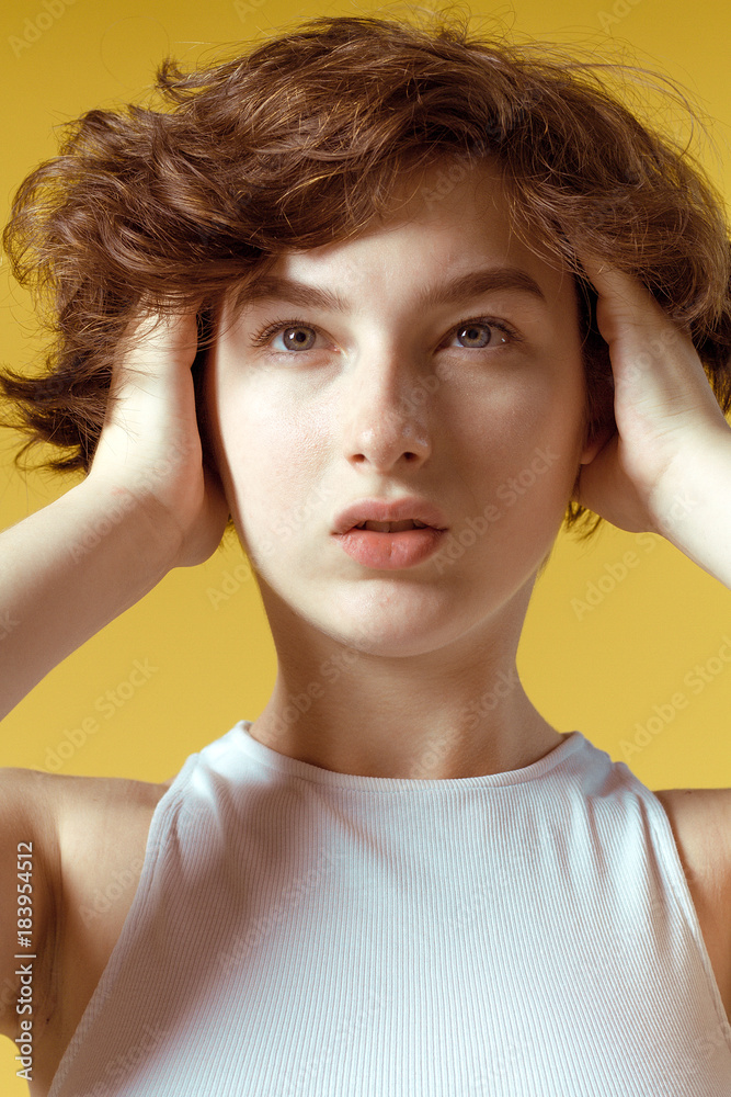 Beautiful and emotional girl on a yellow background without make-up and with natural skin Beautiful and emotional girl on a yellow background without make-up and with natural skin