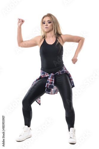 Mid action moving posture of woman dance aerobics instructor looking down and moving arms. Full body length portrait isolated on white background. 