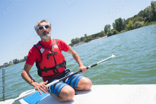 mature attractive rider contemplating nature sitting on paddle board