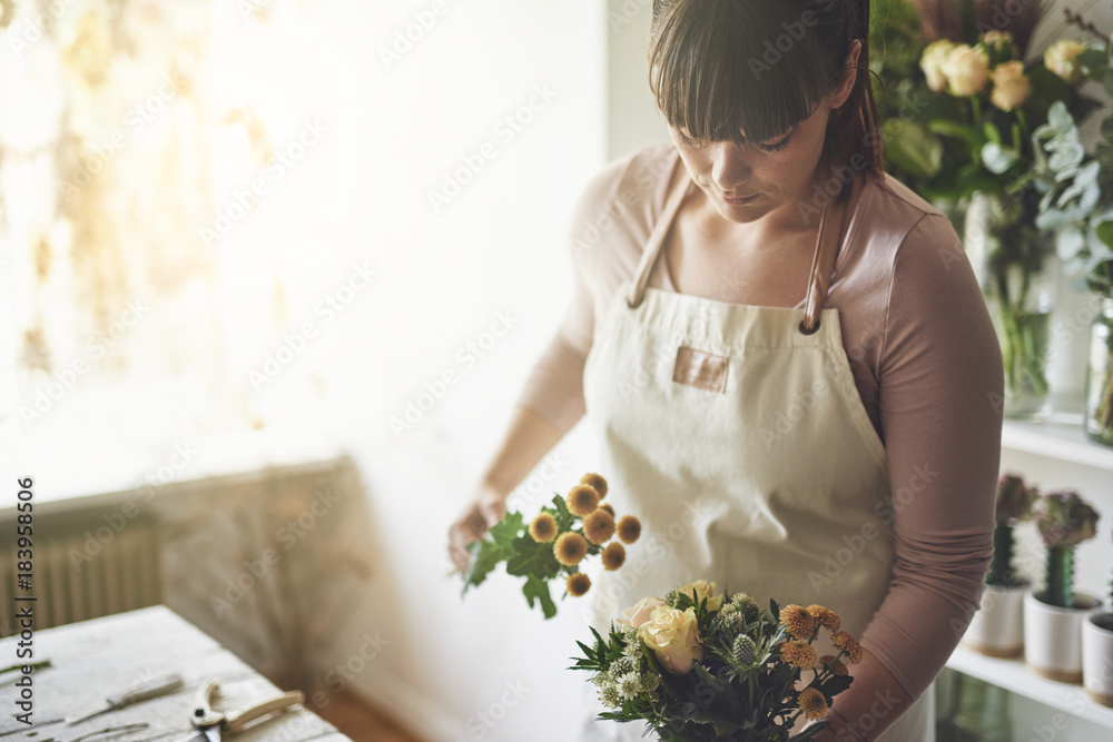 Young florist making a bouquet in her flower shop - obrazy, fototapety, plakaty 