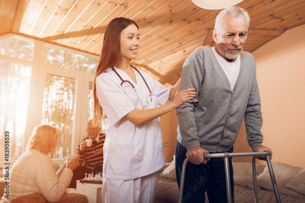 Fototapeta premium An asian nurse helps a man on an adult walker in a nursing home.