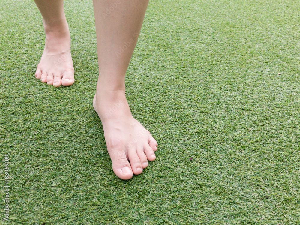 Foots steping forward on grass field close up.