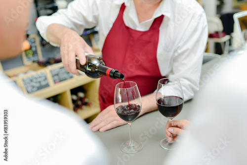 Worker pouring red wine into glasses
