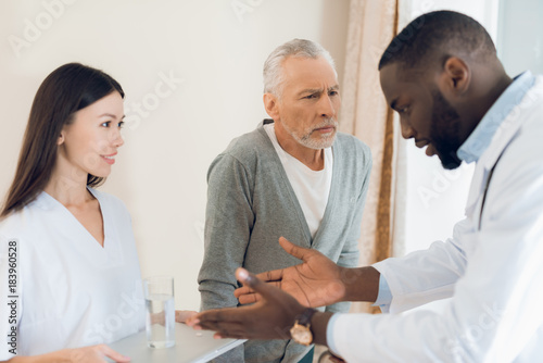 The doctor tells the nurse how an elderly male patient should take pills.