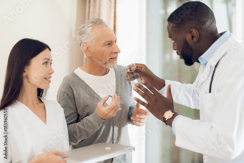 The doctor tells the nurse how an elderly male patient should take pills.