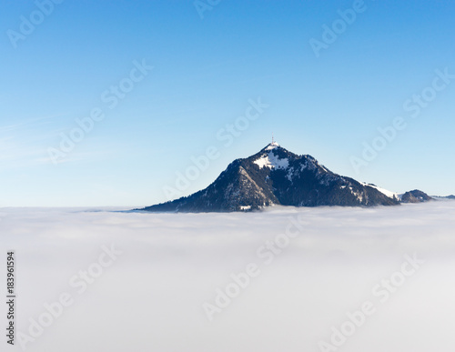 Mountain stick out of foggy cloud layer. Gruenten, Bavaria, Germany. Foresight and vision for business concept and ideas.