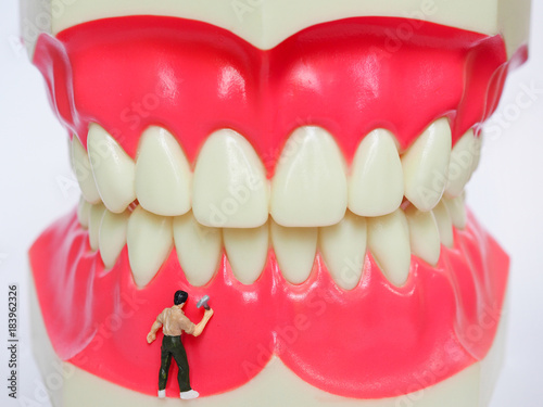 Miniature worker on plastic teeth of removable denture. Dental health concept.