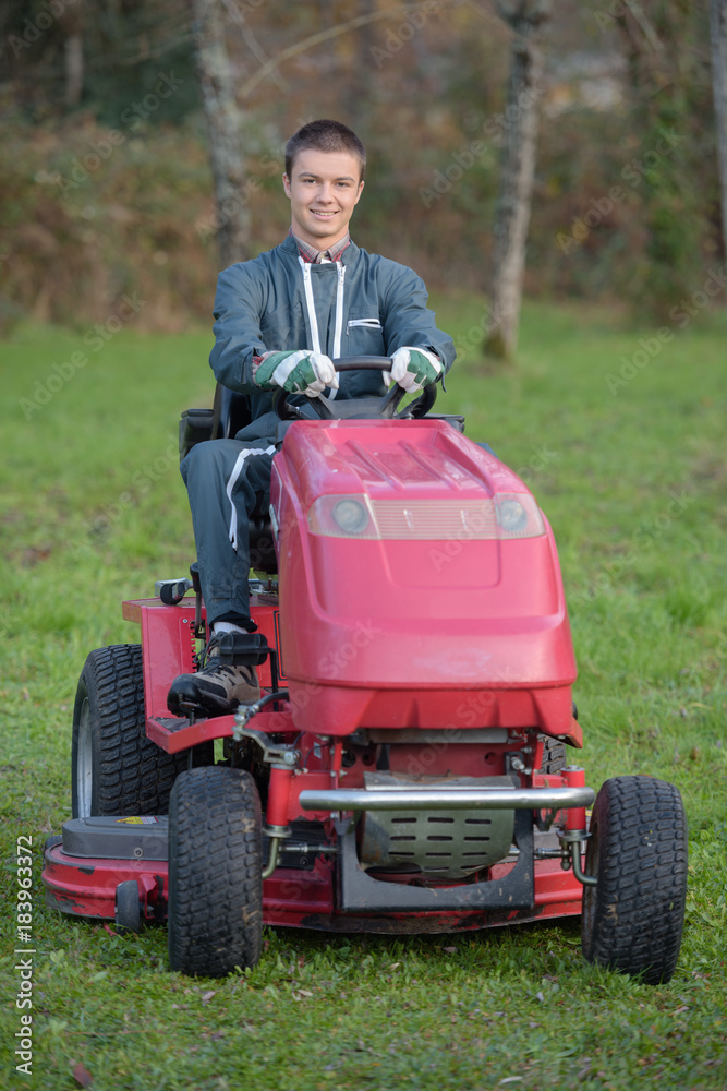 Fototapeta premium young gardener on a lawn tractor
