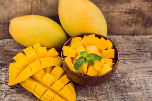 Mango fruit and mango cubes on the wooden table photo