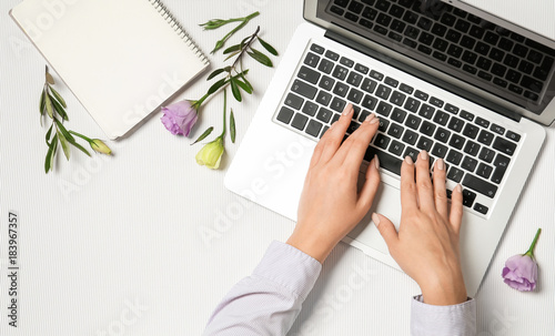 Young woman using laptop for online shopping on light background