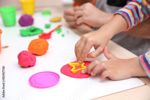 Little children engaged in playdough modeling at daycare, closeup photo