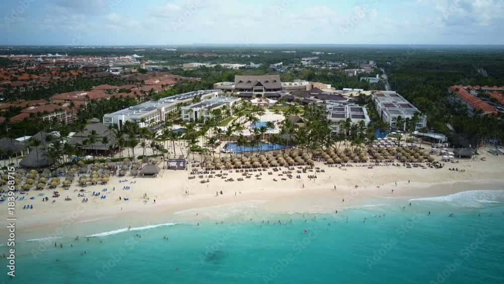 Look from above at the golden beach with resting people and blue ocean before them.