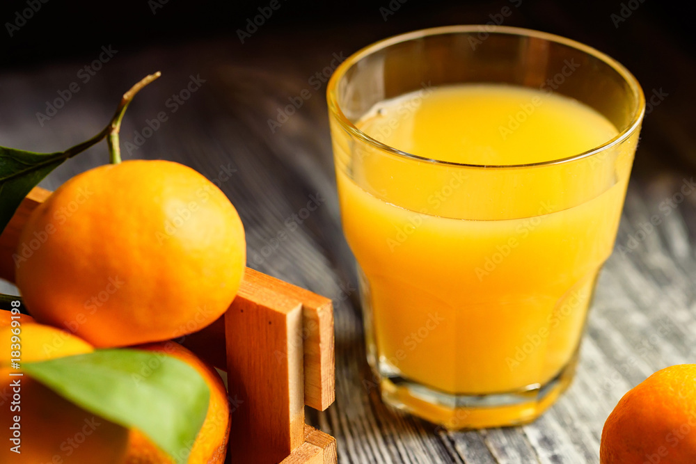Fototapeta premium Glass of fresh juice and mandarins on table