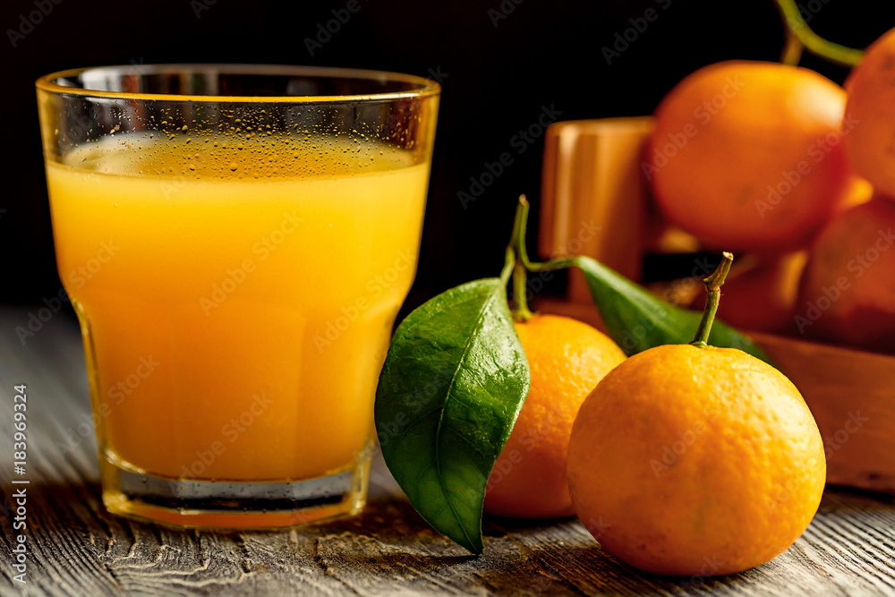 Glass of fresh juice and mandarins on table