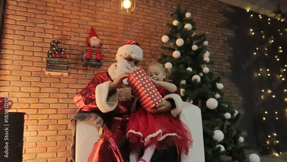 girl sitting at santa lap, happy kid telling papa noel his christmas wishes, smiling young lady