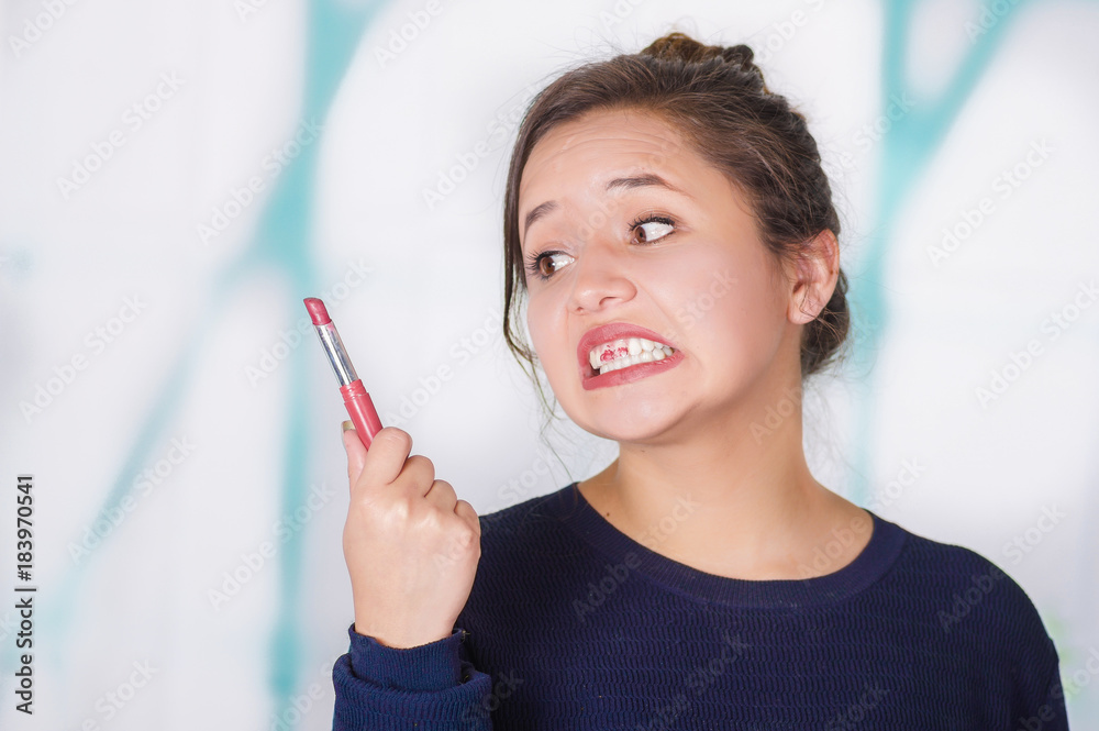 Close up of surprise beautiful woman doing miss lip with pink lipstick in a blurred background Close up of surprise beautiful woman doing miss lip with pink lipstick in a blurred background