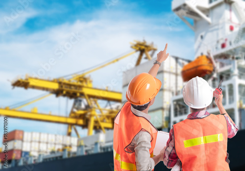 Dock worker pointing finger on control of container loading in an industrial harbor