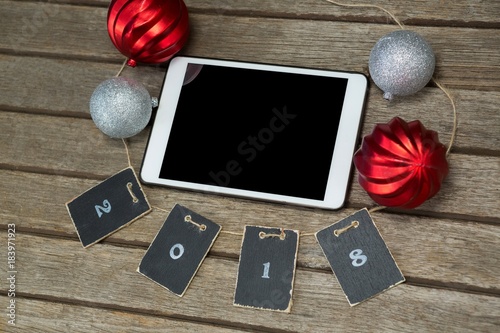 Baubles and cards forming 2018 around the digital tablet