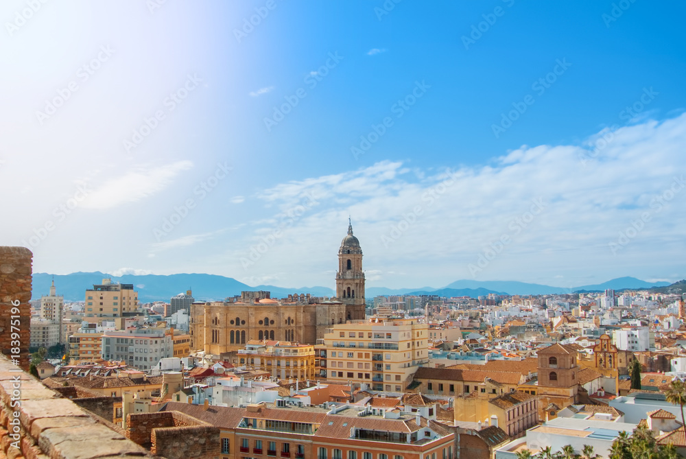 Aerial panoramic view over the roofs to a tower of Malaga Cathedral from the walls and towers of Castillo Gibralfaro (Castle of Gibralfaro) on sunny day, Andalusia, Spain.