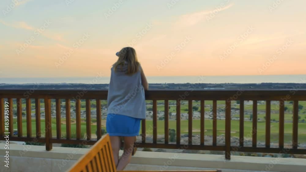 Pretty woman enjoys a beautiful evening view from terrace Pretty woman enjoys a beautiful evening view from terrace
