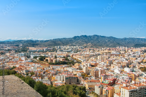 A view to the city center of Malaga and its surroundings with mountains at the background from old medieval walls of the Gibralfaro Castle of Malaga  Andalusia  Spain  on sunny evening.