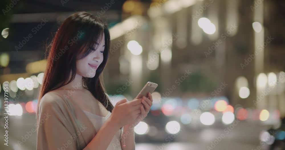 beautiful Asian girl in the night metropolis, uses a smartphone for communication, writes the message with a smile, Steadicam shot