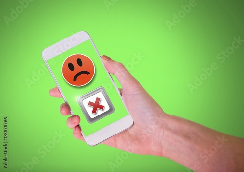 Hand holding phone with sad smiley face and X negative wrong