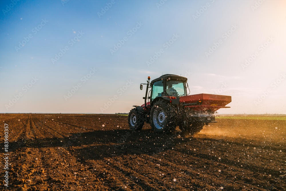 Fototapeta premium Farmer fertilizing arable land with nitrogen, phosphorus, potassium fertilizer