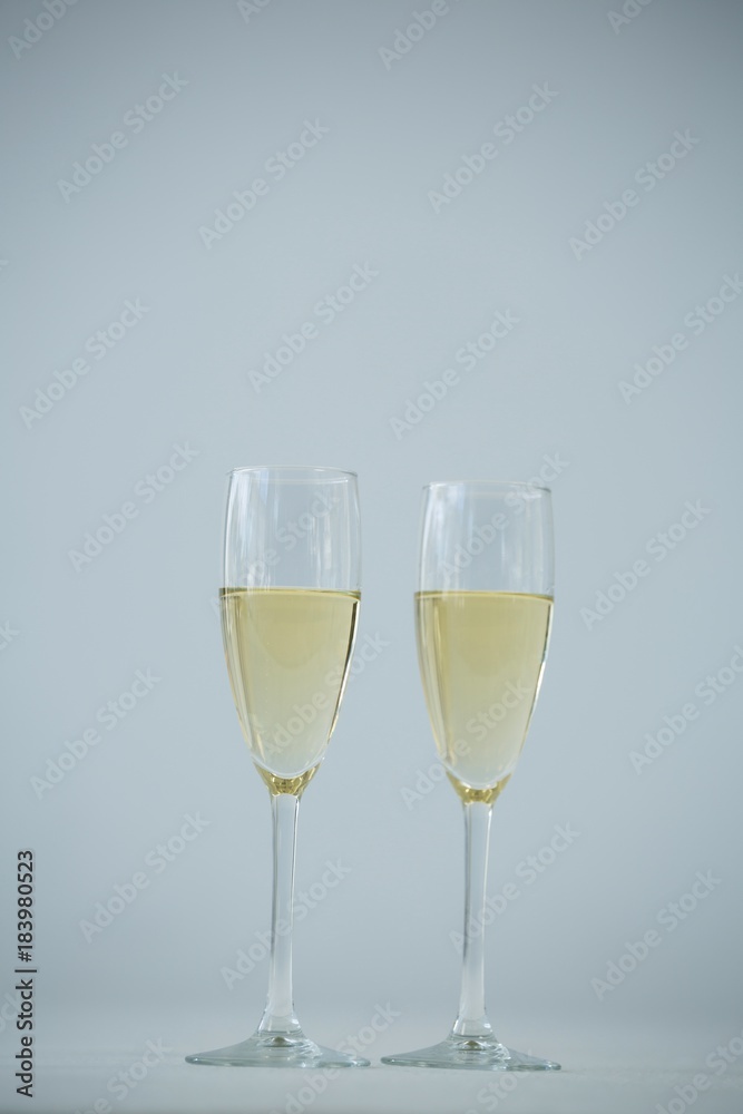 Two champagne flutes against white background