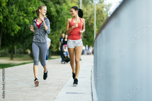 Two sporty women jogging in city