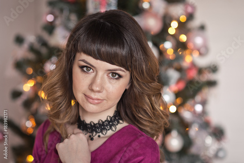 Close-up portrait of girl in red dress on the background of Christmas deco