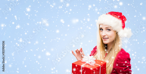 Attractive and beautiful girl in Christmas hat over winter background with snowflakes.