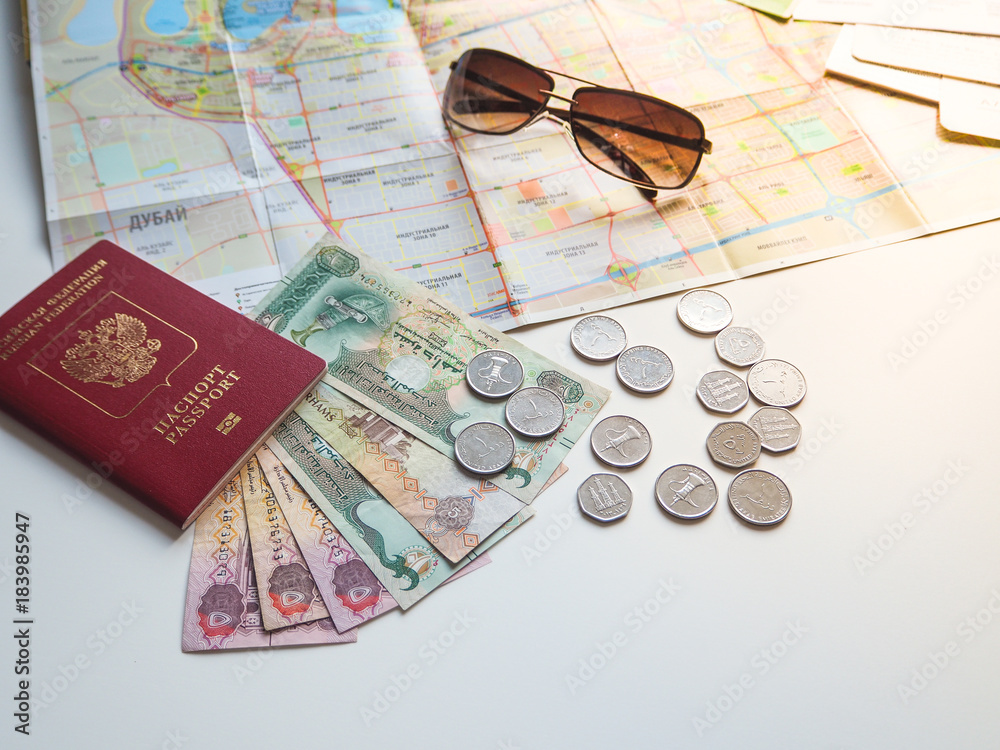 Fototapeta premium Arab dirhams and a Russian passport on the background of the card and sunglasses. The concept of travel. 