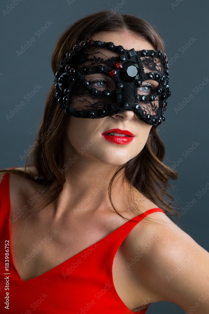 Obraz premium Woman wearing masquerade mask against black background