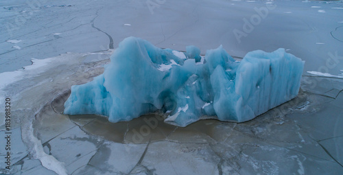 Aerial photo of blue iceberg in frozen lagoon, Fjallsárlón Iceland