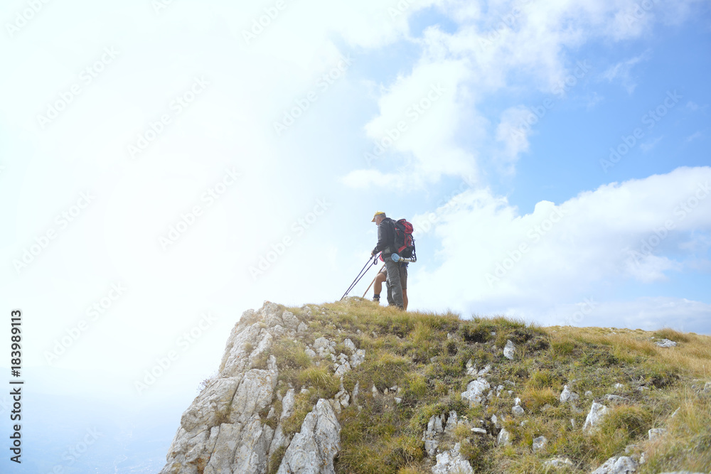 Hikers with backpacks relaxing on top of a mountain and enjoying the view of valley Hikers with backpacks relaxing on top of a mountain and enjoying the view of valley