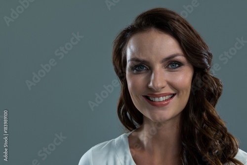 Smiling woman looking at camera against grey background