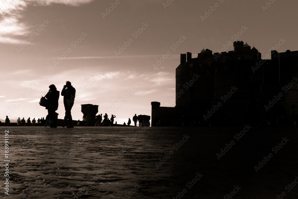 Silhouetted tourists explore the front of Edinburgh Castle