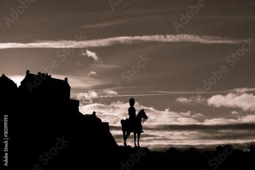 Edinburgh Castle and military statue silhoeutted against a cloudy dusk sky