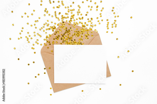 Styled desk with envelope, blank card and golden confetti isolated on a white background. Flat lay. Mockup template. View from above
