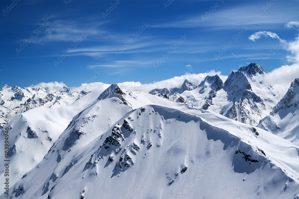 Winter mountains with snow cornice and blue sky with clouds