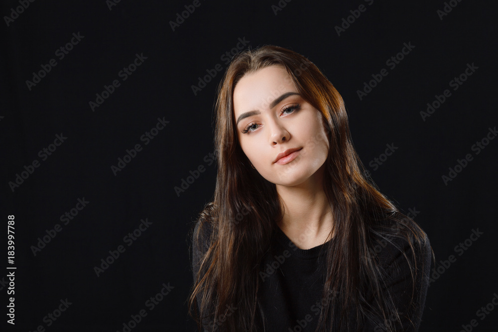 Low key portrait of young adorable caucasian woman in black sweater on dark background. Facial expressions and emotion concept.