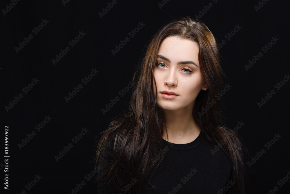 Low key portrait of young adorable caucasian woman in black sweater on dark background. Facial expressions and emotion concept.