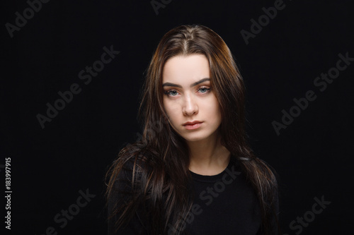 Low key portrait of young adorable caucasian woman in black sweater on dark background. Facial expressions and emotion concept.