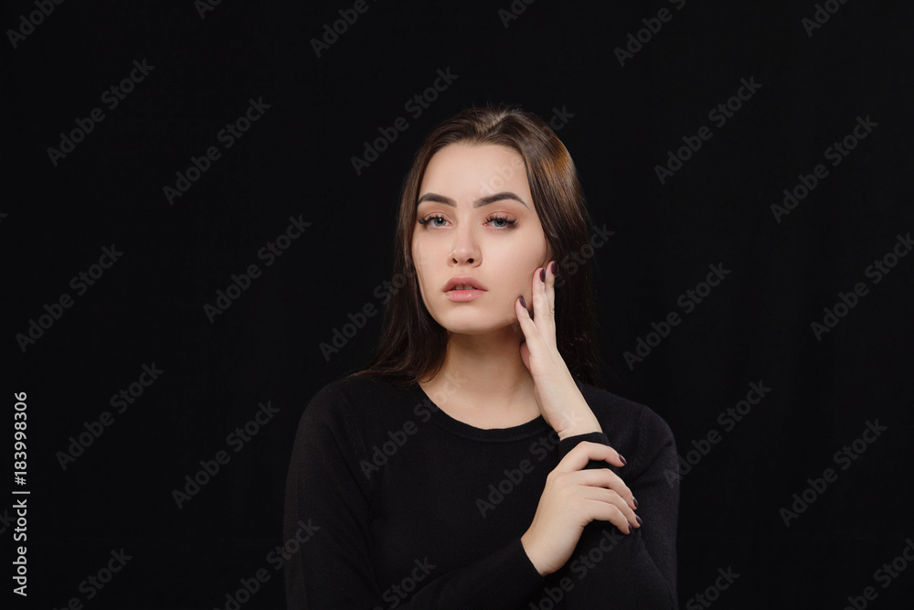 Obraz premium Low key portrait of young adorable caucasian woman in black sweater on dark background. Facial expressions and emotion concept.