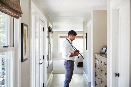 Young man at home tying his tie as he gets ready for work