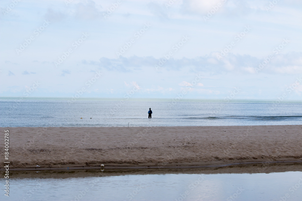 background of beach with tiny fisherman in the sea