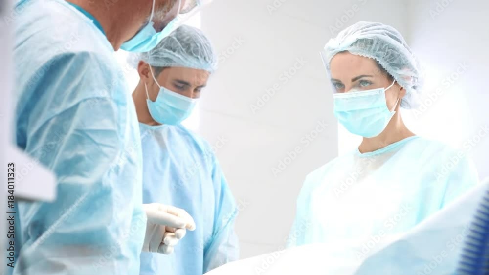 Three doctors performs surgical operation in surgery room Three doctors performs surgical operation in surgery room